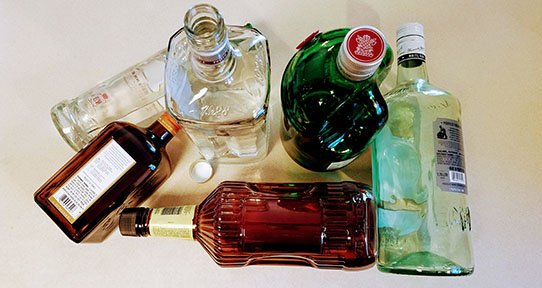 A photo of several empty bottles of spirits on a plain white background.