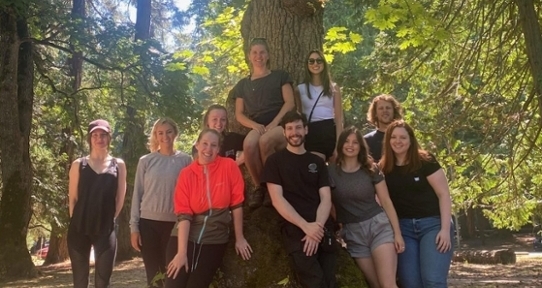 a group of people outside posing in front of a tree 