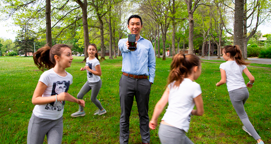 Dr. Sam Liu, an East Asian man, holding up a smartphone surrounded by four images of a young girl running.