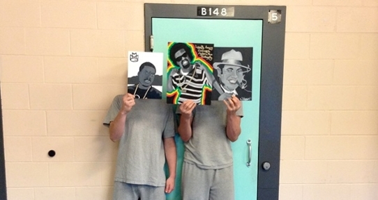 Participants in the Youth in Custody project hold art in front of their faces.