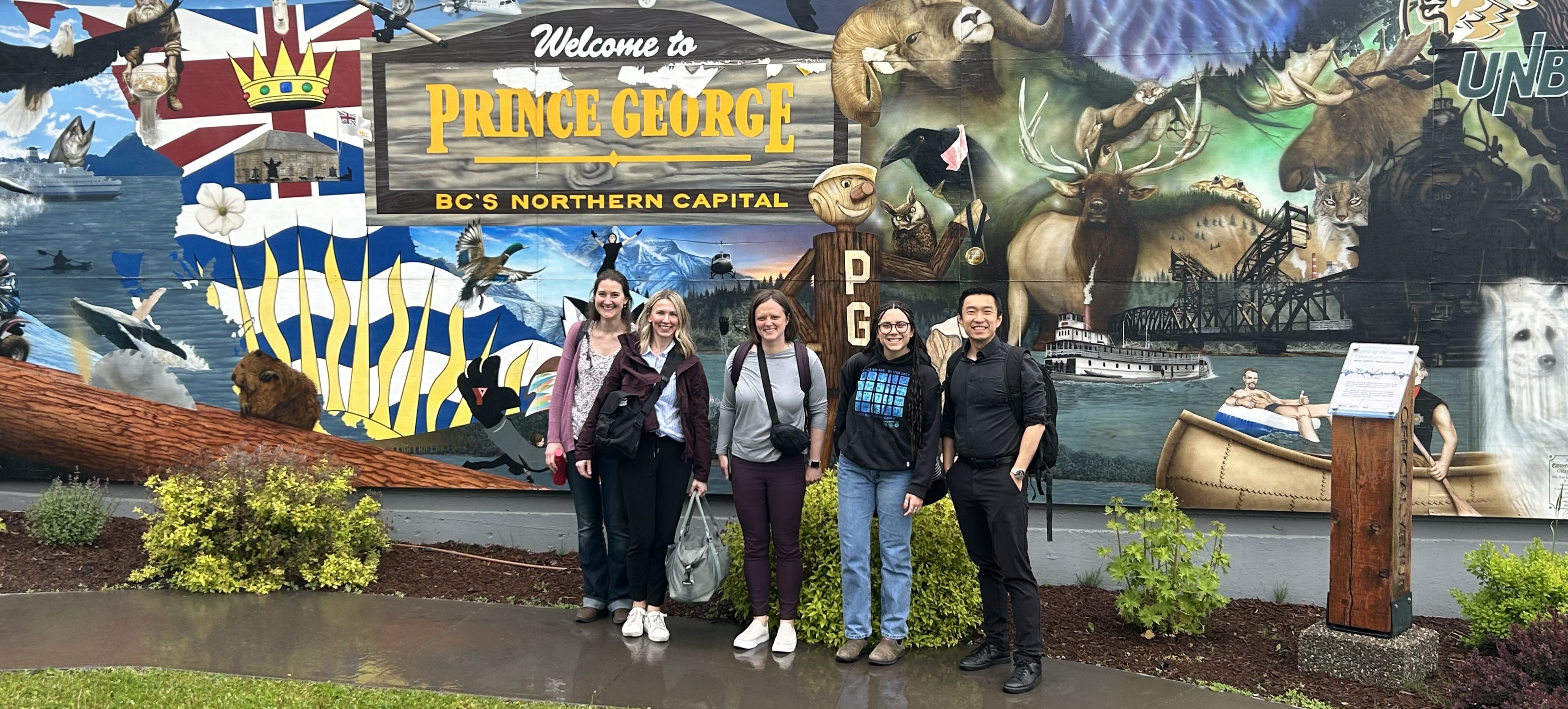 Research team standing in front of Prince George mural