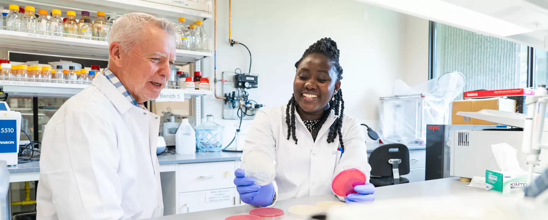 A graduate student and her supervisor look at an agar plate. 