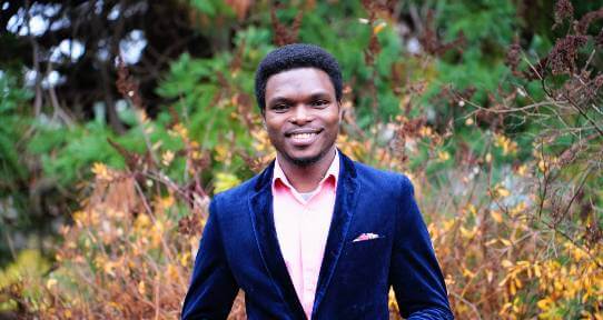Kenny Olobatuyi wearing a pink dress shirt and blue blazer