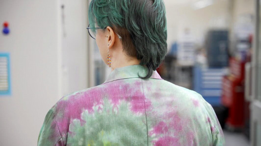 Headshot form behind of person in a tye dye lab coat