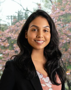Smiling head shot of Dr. Nicolette Fonseca in front of cherry trees in blossom