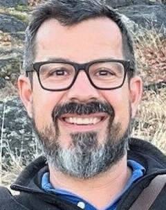 Smiling headshot of Dr. Chris Nelson in front of a rocky hill. 