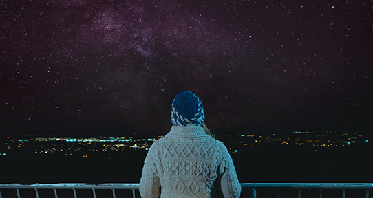 Woman looking at the night sky above a city