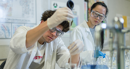 Two students in lab coats in a SEOS lab