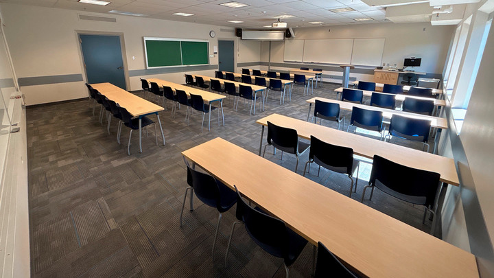 View from the back of the room showing rows of tables and chairs facing the presenter area.