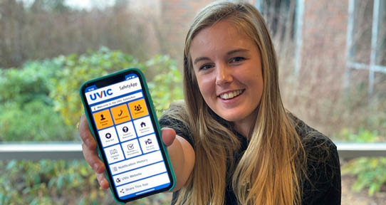 UVic student holds out a smart phone with the UVic Safety App showing on it