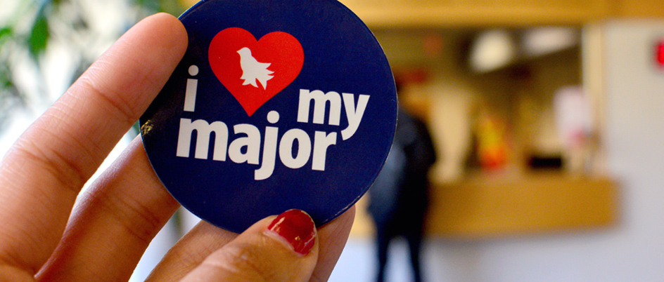 Hand holding a button that says 'I love my major'