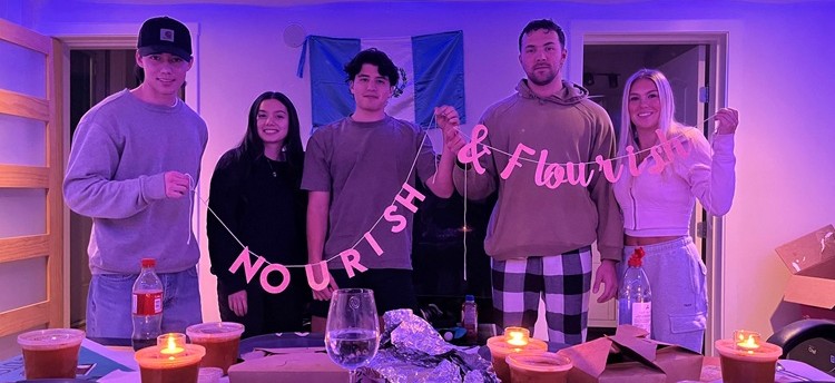 A group of students holding a banner that says "Nourish & Flourish"