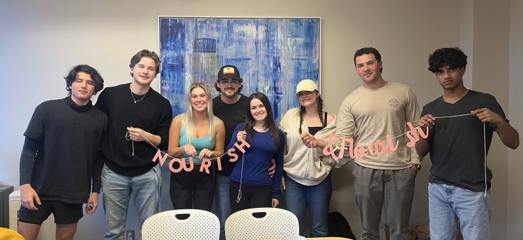 A group of students holding a banner that says "Nourish & Flourish"