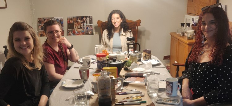 A group of students around a dinner table, smiling at the camera