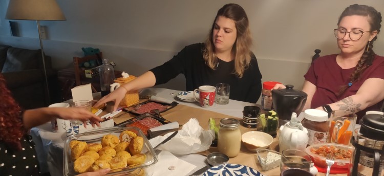 A group of students at a dinner table, passing around buns