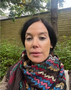 Photo of Anna from shoulders up. She's wearing a colourful scarf.