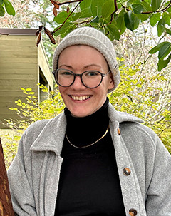 Photo of Annette wearing a grey toque and black rimmed glasses