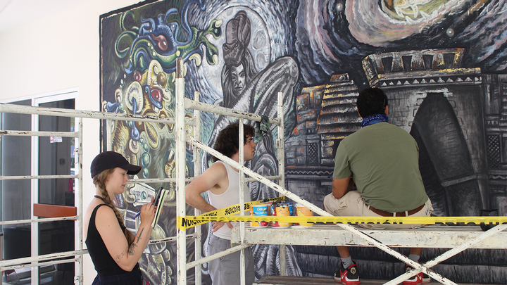 student in front of mural