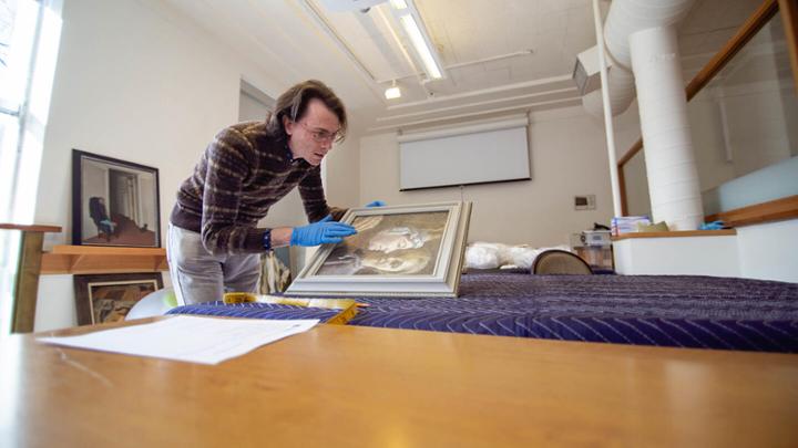 A UVic anthropology student examines a painting in a museum's lab