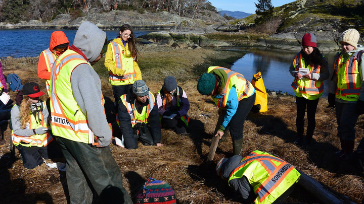 Dr Darcy Mathews and field school students examine terrain during an environmental study on Tl'ches.
