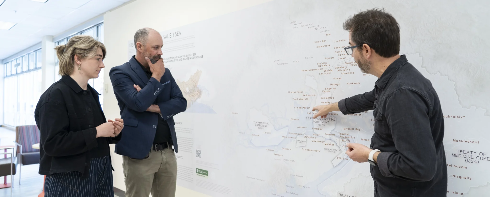 Brian Thom (right) points to treaties on the map during a discussion with Ry Moran (centre) and Leah Fulton (left). Credit: UVic Photo Services