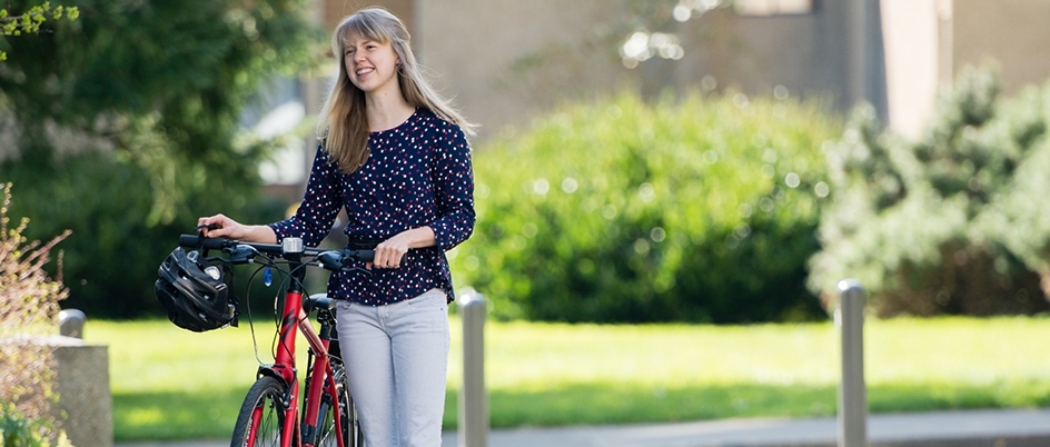 Student walking a bike on campus