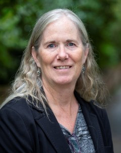 Photo of Leslie in front of a green nature background