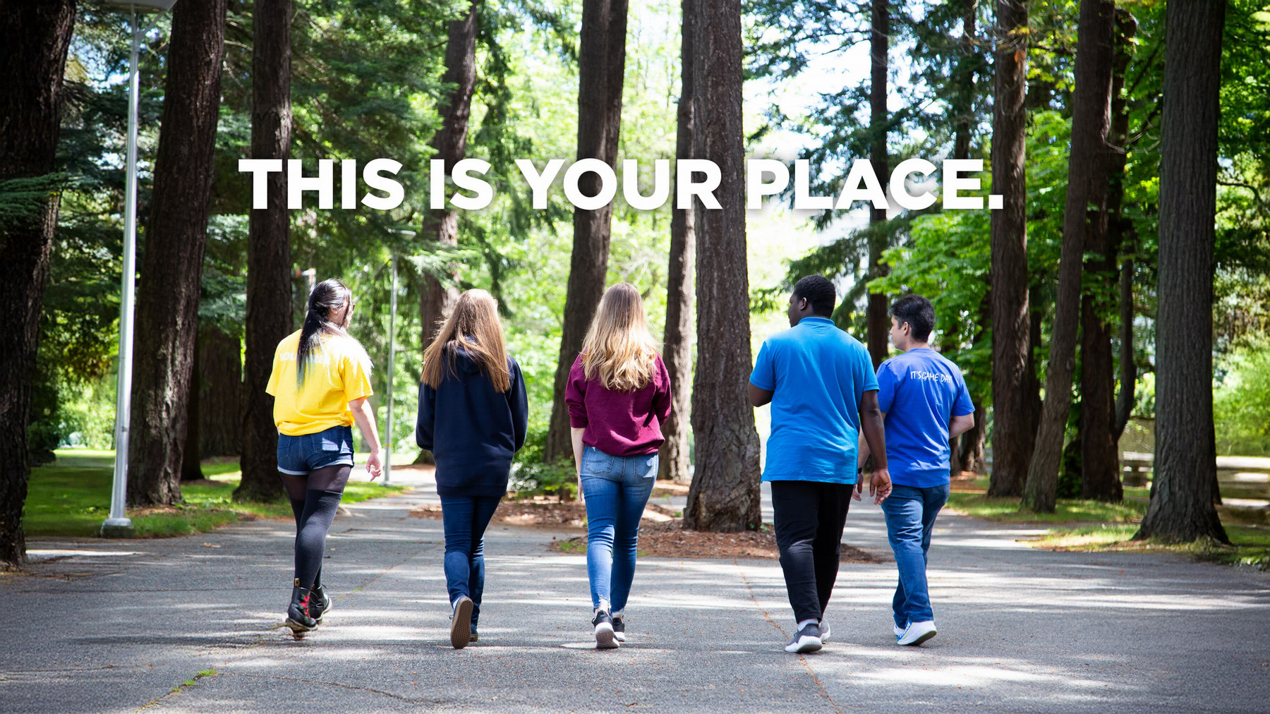 five students walking among tall trees on campus, with the text THIS IS YOUR PLACE above them