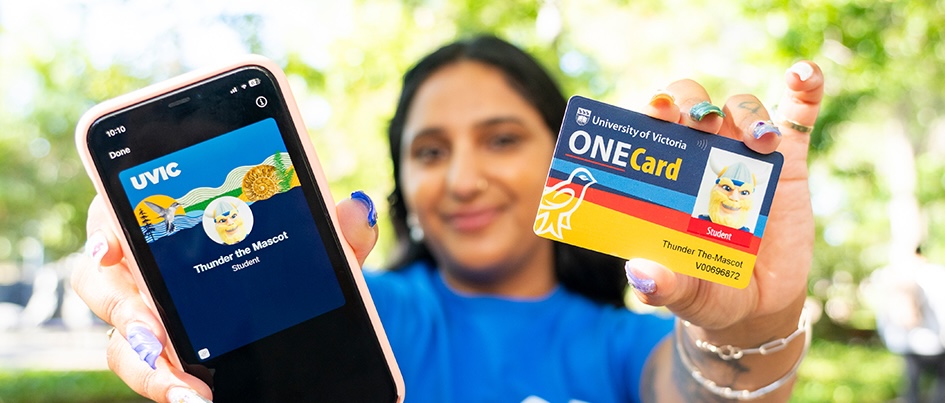 Staff member holds up UVic ONECard in one hand and mobile phone with ONECard app in other.