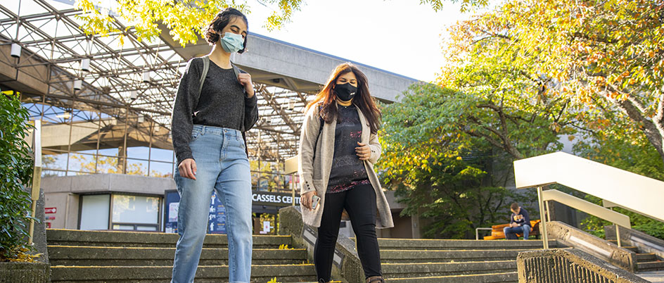 Two students wearing masks walk in front of the Jamie Cassels Centre
