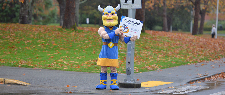 Thunder mascot holds a stocktober sign and waves at camera