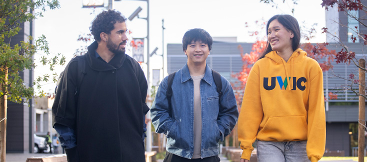 Three students walking in front of the new residence buildings.