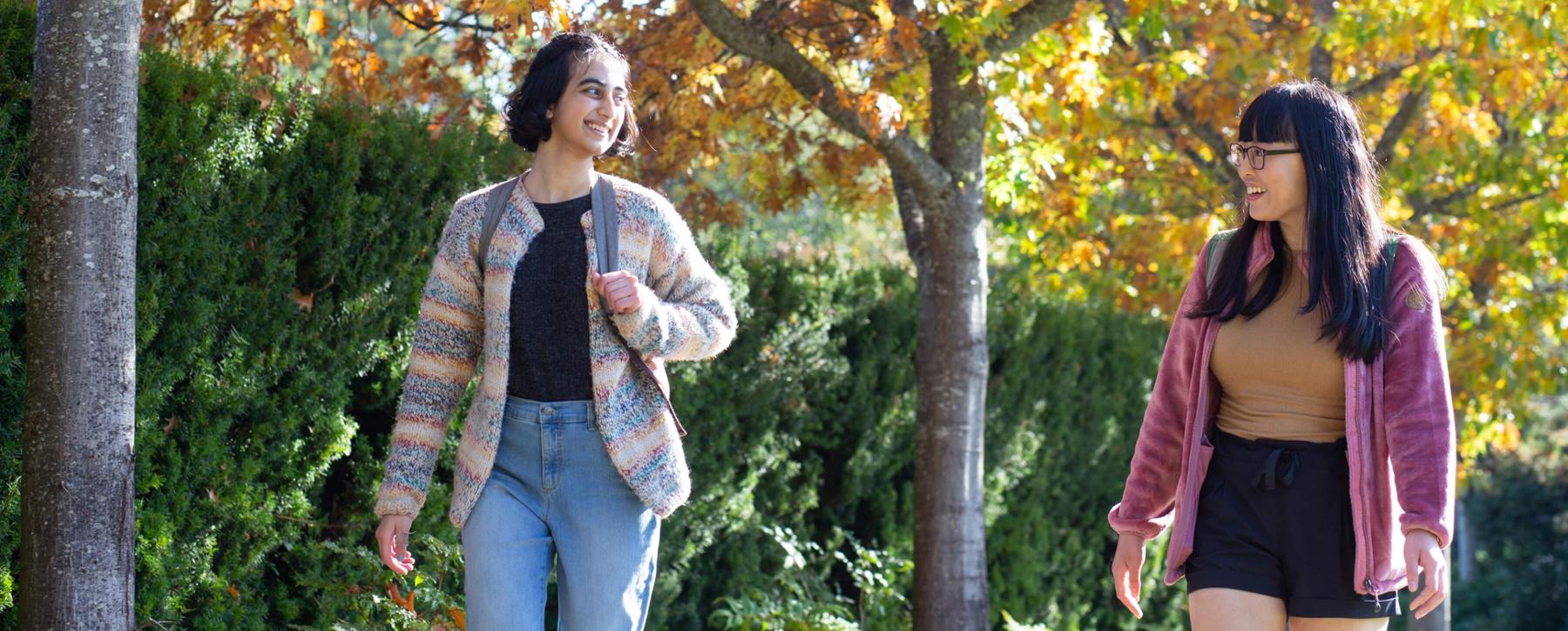 Two students walk on UVic campus in the fall.