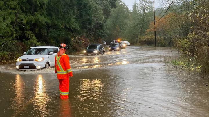 A highway safety worker coordinates vehicles stuck in rising floodwaters.