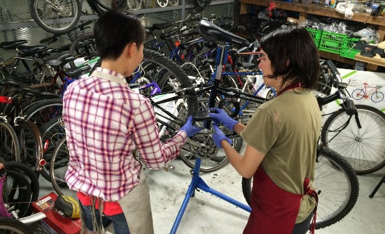 two individuals repairing an old bike in the bike repair as part of UVic's bike loan program