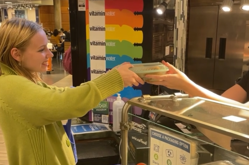 student accepting ecobox container at food kiosk in mystic market