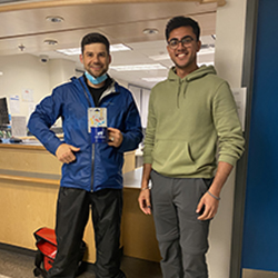 CyberAware 2022 winner. Two people standing in front of the Computer Help Desk holding the gift card and mug prize