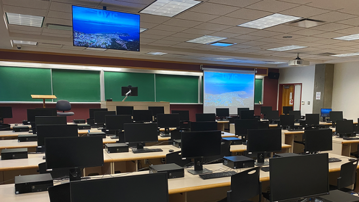 Large classroom with rows of computer desks facing instructor station.