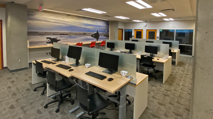 An open space with rows of computer desks and counter high seating.