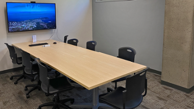 Small meeting room with conference table and television on wall