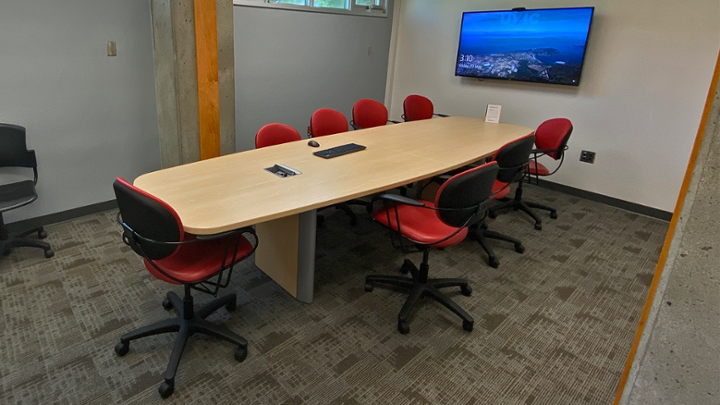 Small meeting room with conference table and television on wall