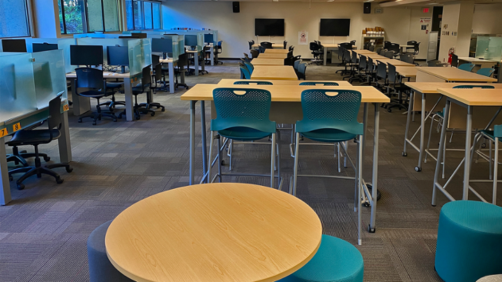 Large classroom with computers around edge of room, rows of tables in middle.