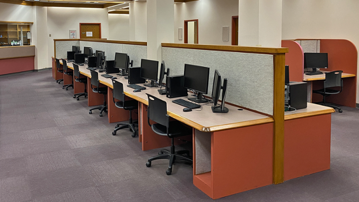 An open space with long row of computer desks in centre.