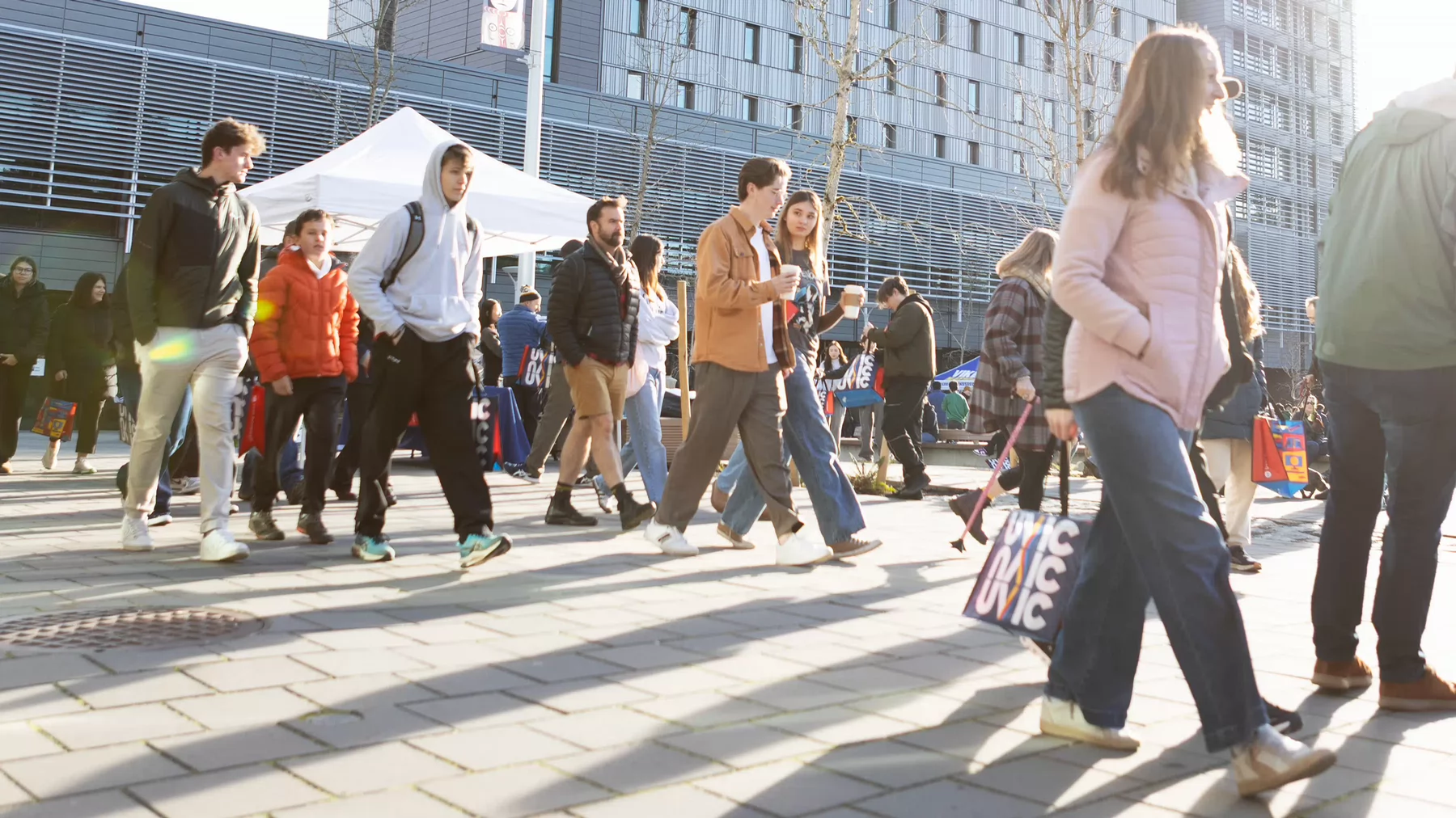 Students walking in the courtyard of a university. A large university residence building is behind.