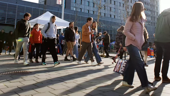 Students walking in the courtyard of a university. A large university residence building is behind.