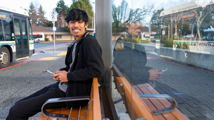 Stave sitting at a bus stop bench at the UVic bus loop