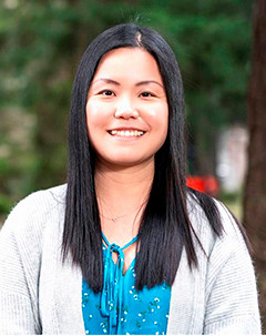 A smiling Chinese woman wearing white cardigan and a blue shirt.