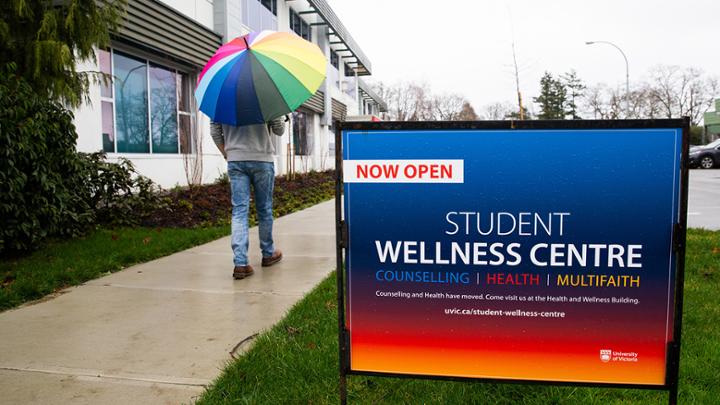 UVic student walking past Student Wellness Centre sign